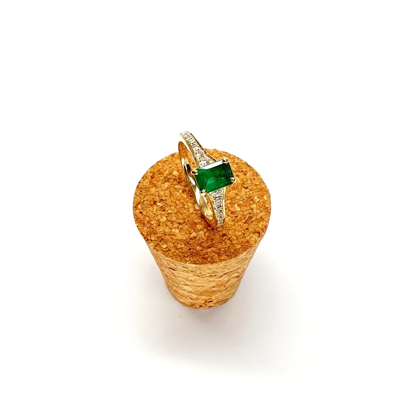 Angled view of emerald ring on textured cork