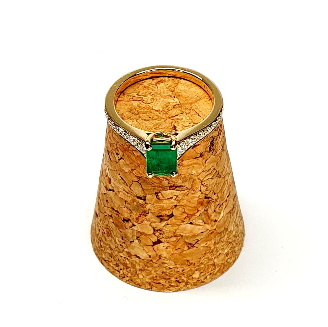 Diamond and emerald ring balanced on cork edge showing claw detail