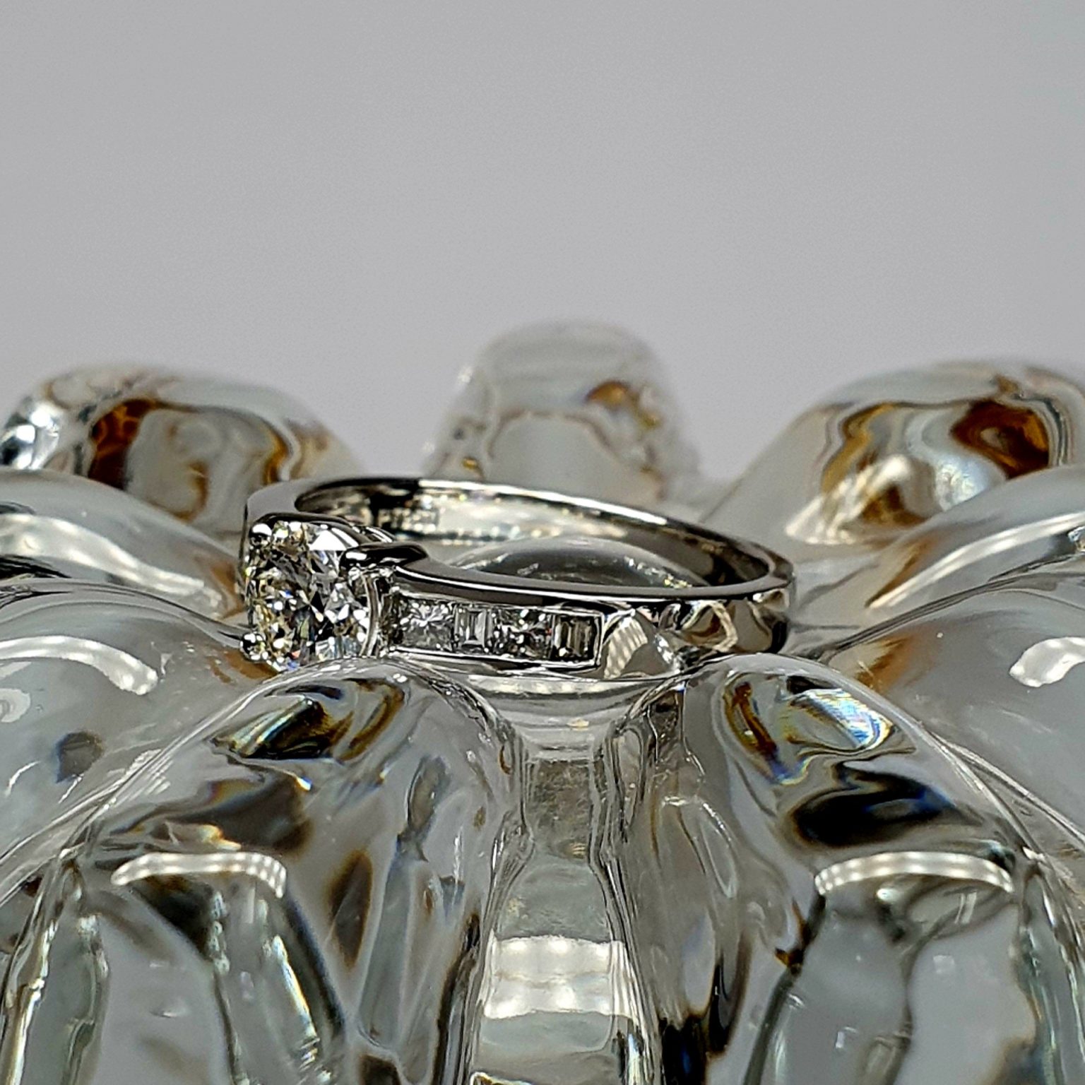 The Lambeth Platinum Diamond Engagement Ring RPT00045 The centre is set with a 0.70ct round brilliant-cut diamond of Colour H clarity SI1, which has an excellent cut, proportions, and symmetry. The side shoulders are channel set with a total of four princess-cut diamonds and four baguette-cut diamonds. The total diamond weight is 1.08 carats.