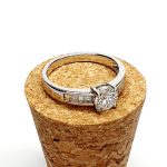 The Lambeth Platinum Diamond Engagement Ring RPT00045 The centre is set with a 0.70ct round brilliant-cut diamond of Colour H clarity SI1, which has an excellent cut, proportions, and symmetry. The side shoulders are channel set with a total of four princess-cut diamonds and four baguette-cut diamonds. The total diamond weight is 1.08 carats.