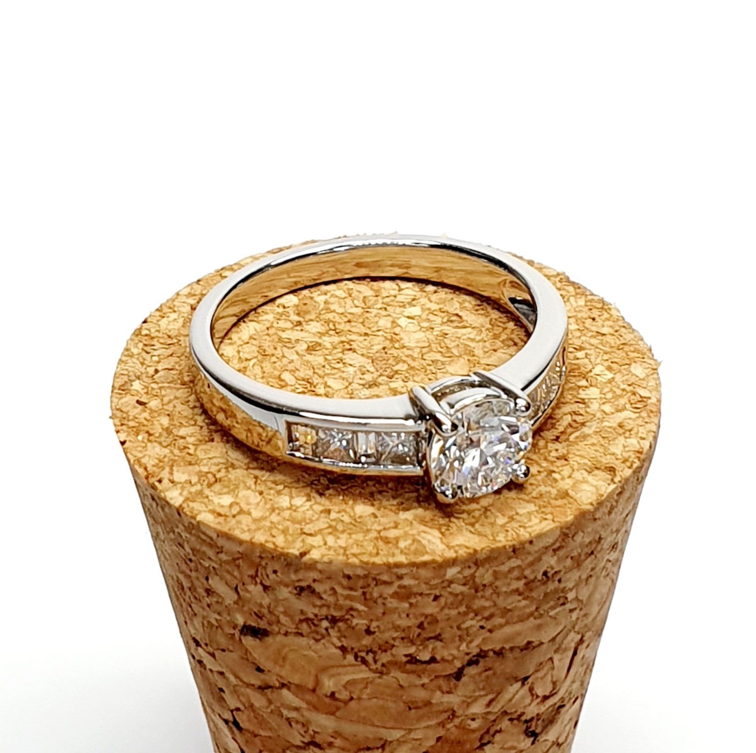 The Lambeth Platinum Diamond Engagement Ring RPT00045 The centre is set with a 0.70ct round brilliant-cut diamond of Colour H clarity SI1, which has an excellent cut, proportions, and symmetry. The side shoulders are channel set with a total of four princess-cut diamonds and four baguette-cut diamonds. The total diamond weight is 1.08 carats.