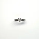 The Lambeth Platinum Diamond Engagement Ring RPT00045 The centre is set with a 0.70ct round brilliant-cut diamond of Colour H clarity SI1, which has an excellent cut, proportions, and symmetry. The side shoulders are channel set with a total of four princess-cut diamonds and four baguette-cut diamonds. The total diamond weight is 1.08 carats.