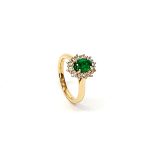 At the heart of this exquisite 18ct yellow gold ring lies a resplendent 7mm x 5mm oval emerald weighing an impressive 0.84 carats and exuding an enchanting green hue. Its captivating charm captures the essence of nature's beauty, with twelve dazzling round brilliant-cut diamonds, totalling 0.41 carats, surrounding the emerald. Each stone is meticulously selected to enhance the ring's allure with unparalleled radiance and brilliance, and the basket-wire setting measures 13mm x 10mm.RA00696.