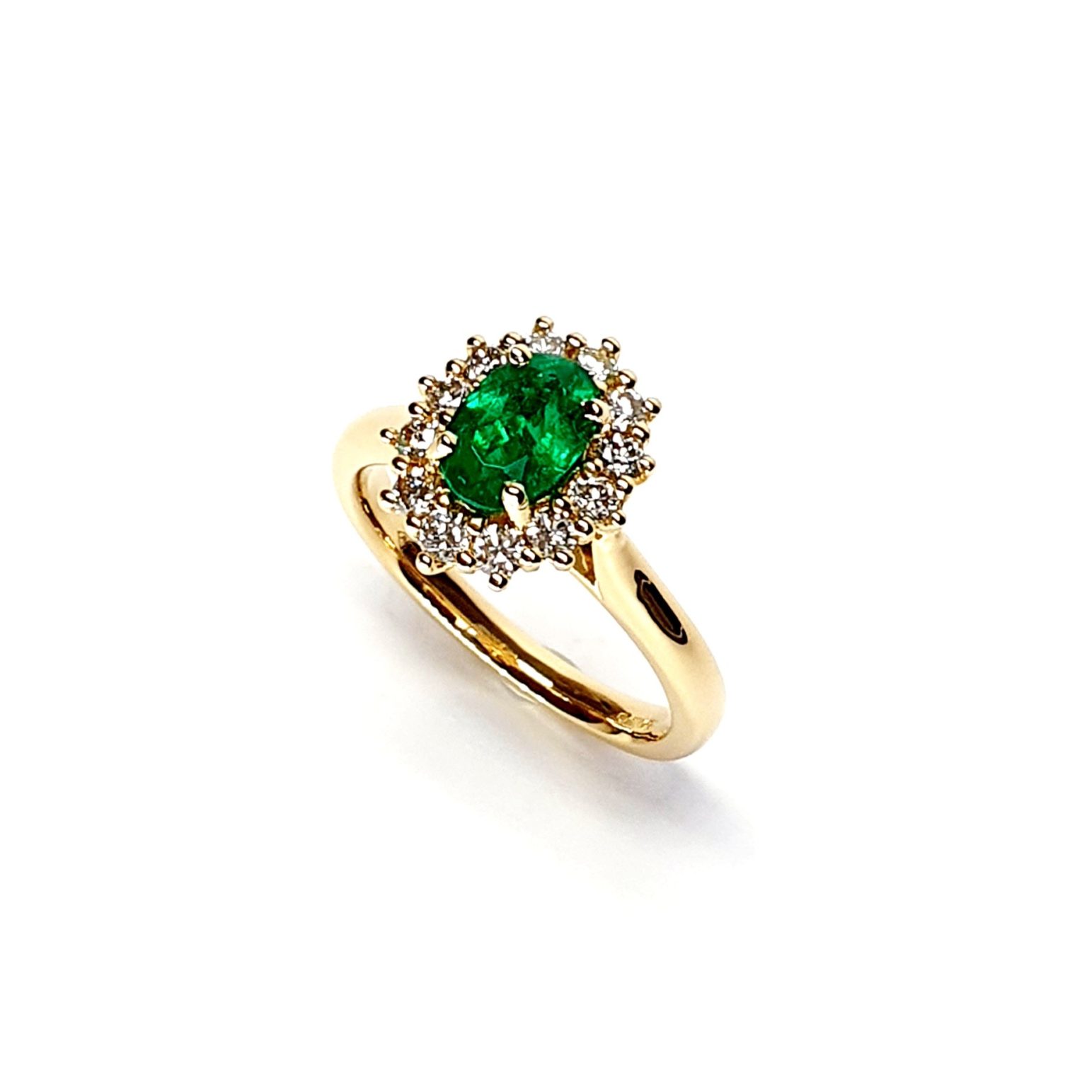 At the heart of this exquisite 18ct yellow gold ring lies a resplendent 7mm x 5mm oval emerald weighing an impressive 0.84 carats and exuding an enchanting green hue. Its captivating charm captures the essence of nature's beauty, with twelve dazzling round brilliant-cut diamonds, totalling 0.41 carats, surrounding the emerald. Each stone is meticulously selected to enhance the ring's allure with unparalleled radiance and brilliance, and the basket-wire setting measures 13mm x 10mm.RA00696.