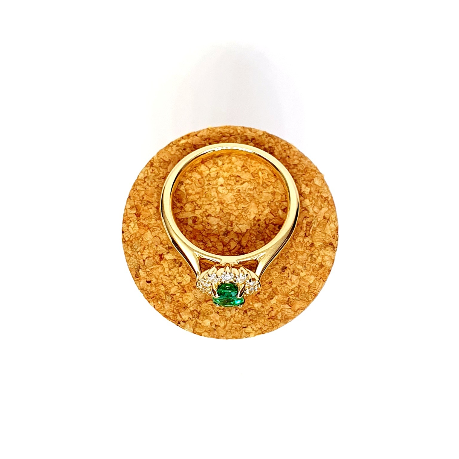 At the heart of this exquisite 18ct yellow gold ring lies a resplendent 7mm x 5mm oval emerald weighing an impressive 0.84 carats and exuding an enchanting green hue. Its captivating charm captures the essence of nature's beauty, with twelve dazzling round brilliant-cut diamonds, totalling 0.41 carats, surrounding the emerald. Each stone is meticulously selected to enhance the ring's allure with unparalleled radiance and brilliance, and the basket-wire setting measures 13mm x 10mm.RA00696.