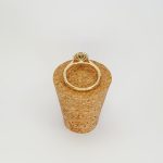 At the heart of this exquisite 18ct yellow gold ring lies a resplendent 7mm x 5mm oval emerald weighing an impressive 0.84 carats and exuding an enchanting green hue. Its captivating charm captures the essence of nature's beauty, with twelve dazzling round brilliant-cut diamonds, totalling 0.41 carats, surrounding the emerald. Each stone is meticulously selected to enhance the ring's allure with unparalleled radiance and brilliance, and the basket-wire setting measures 13mm x 10mm.RA00696.