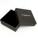 Black cardboard two part box with a black draw string pouch inside. open.