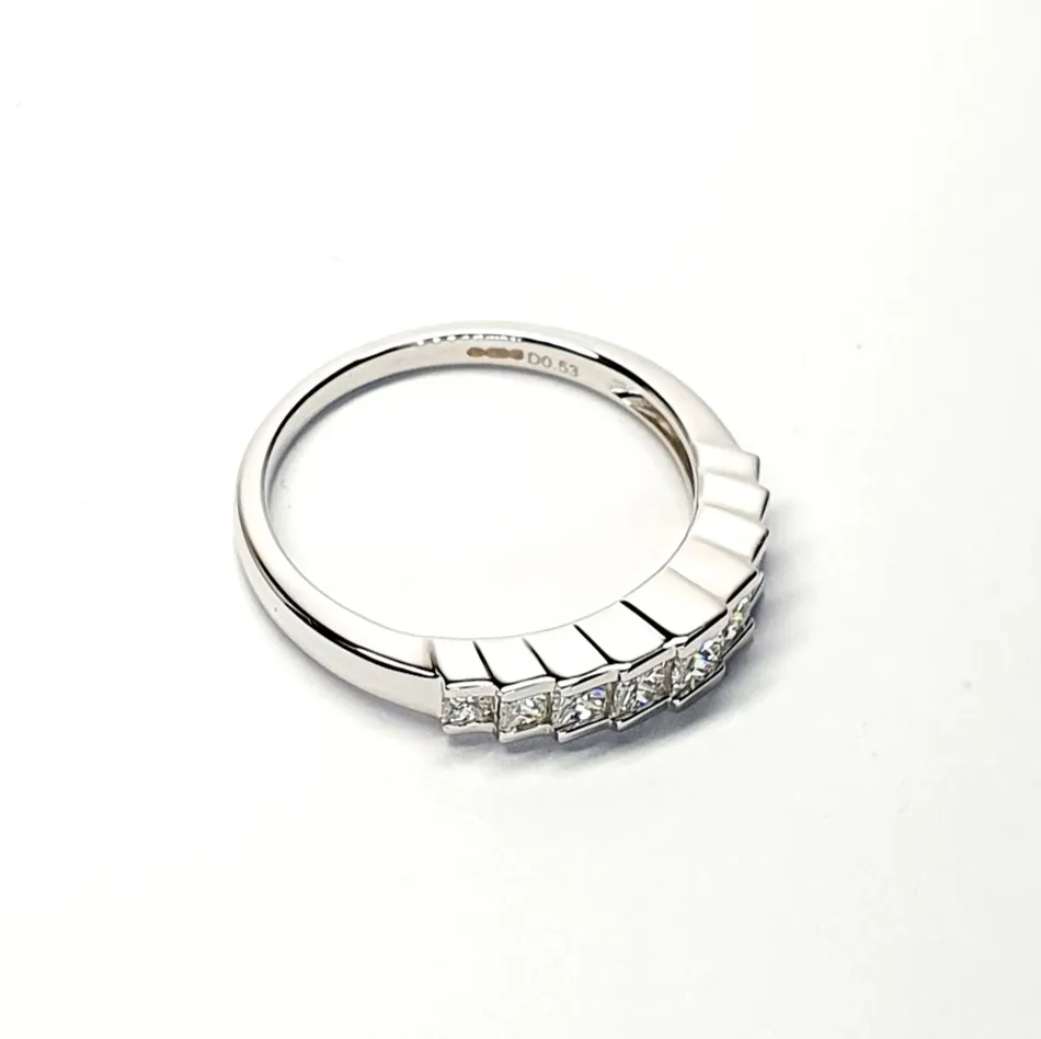 1920s Style Elegance: Against a clean white backdrop, this 18ct white gold ring exudes sophistication with its nine princess-cut diamonds in a step design, inspired by the glamour of 1920s style.