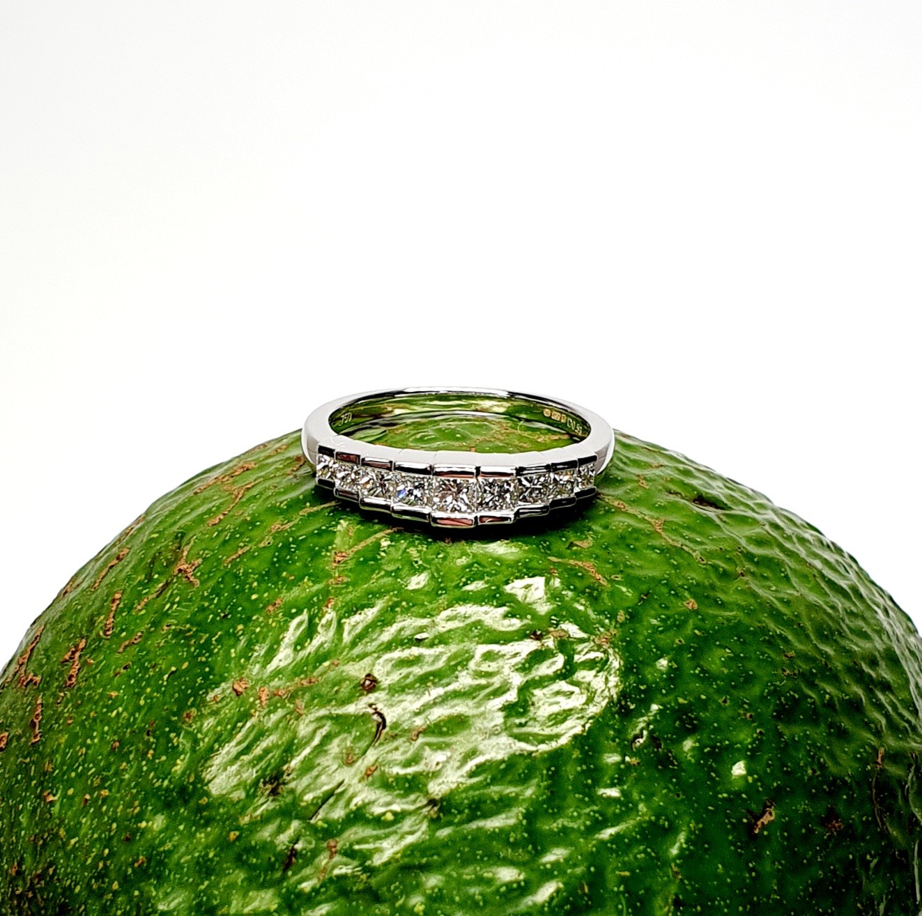 Avocado Elegance: The rich green backdrop of an avocado highlights the brilliance of the nine princess-cut diamonds and the polished 18ct white gold, creating a stunning visual contrast.