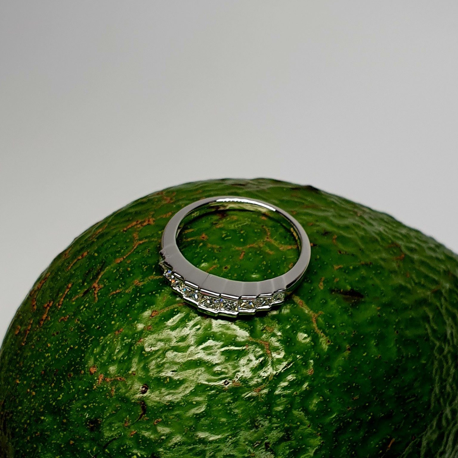 Avocado Elegance: The rich green backdrop of an avocado highlights the brilliance of the nine princess-cut diamonds and the polished 18ct white gold, creating a stunning visual contrast.