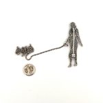 A real silver lady walking a dog on a chain leash brooch set with cubic zirconia with two pins.. Back