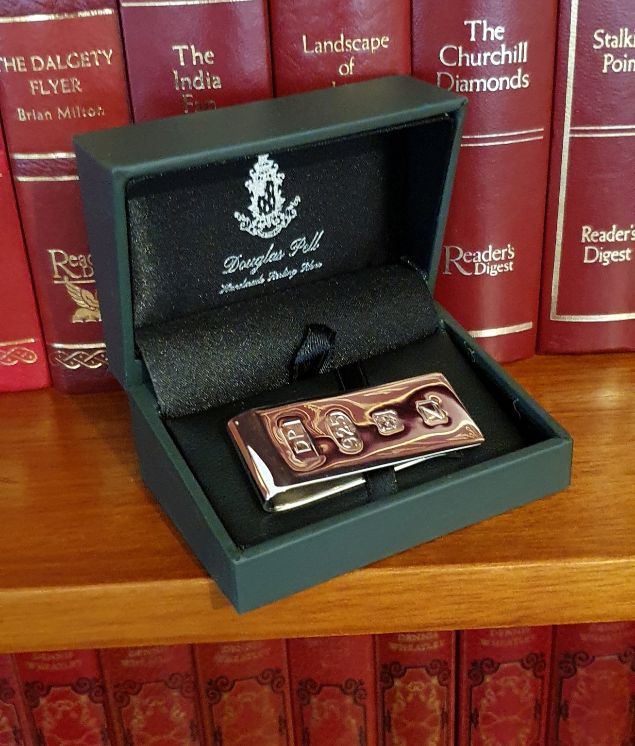 Douglas Pell cash clip Pictured in the box on a bookshelf.