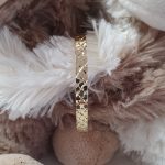 Expanding baby bangle shown in between two cuddling toy teddy bears close up
