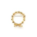 A 9ct yellow gold brooch with a circle of eleven 5mm round pearls leading to a bow to the bottom with three petite round diamonds set to the centre of the bow. Showing back view.