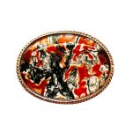 This stunning brooch features a domed oval moss agate stone semi-translucent, exhibits captivating dendritic inclusions. As a result, the stone displays mesmerizing swirls of orangish-red and deep green., exquisitely set in a 9ct yellow gold rub-over setting it is framed by twisted gold wire and includes an open-back bezel to maximizes light exposure. Front view showing light from the back.