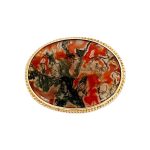 This stunning brooch features a domed oval moss agate stone semi-translucent, exhibits captivating dendritic inclusions. As a result, the stone displays mesmerizing swirls of orangish-red and deep green., exquisitely set in a 9ct yellow gold rub-over setting it is framed by twisted gold wire and includes an open-back bezel to maximizes light exposure. Front view.