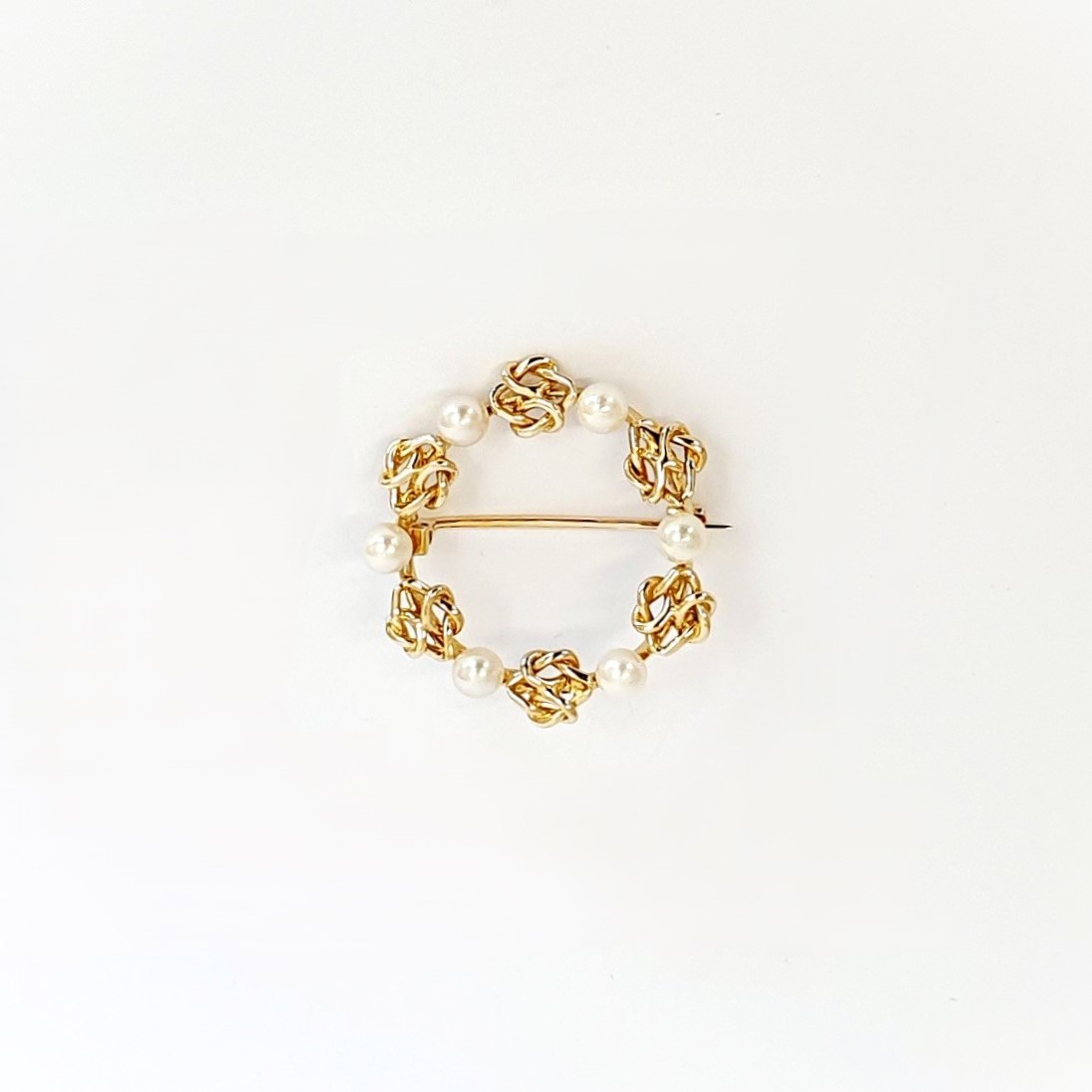 A 9ct yellow gold circle brooch of six 3.8mm pearls & six gold double knots alternately equally spaced in a circle, picture shows front view.