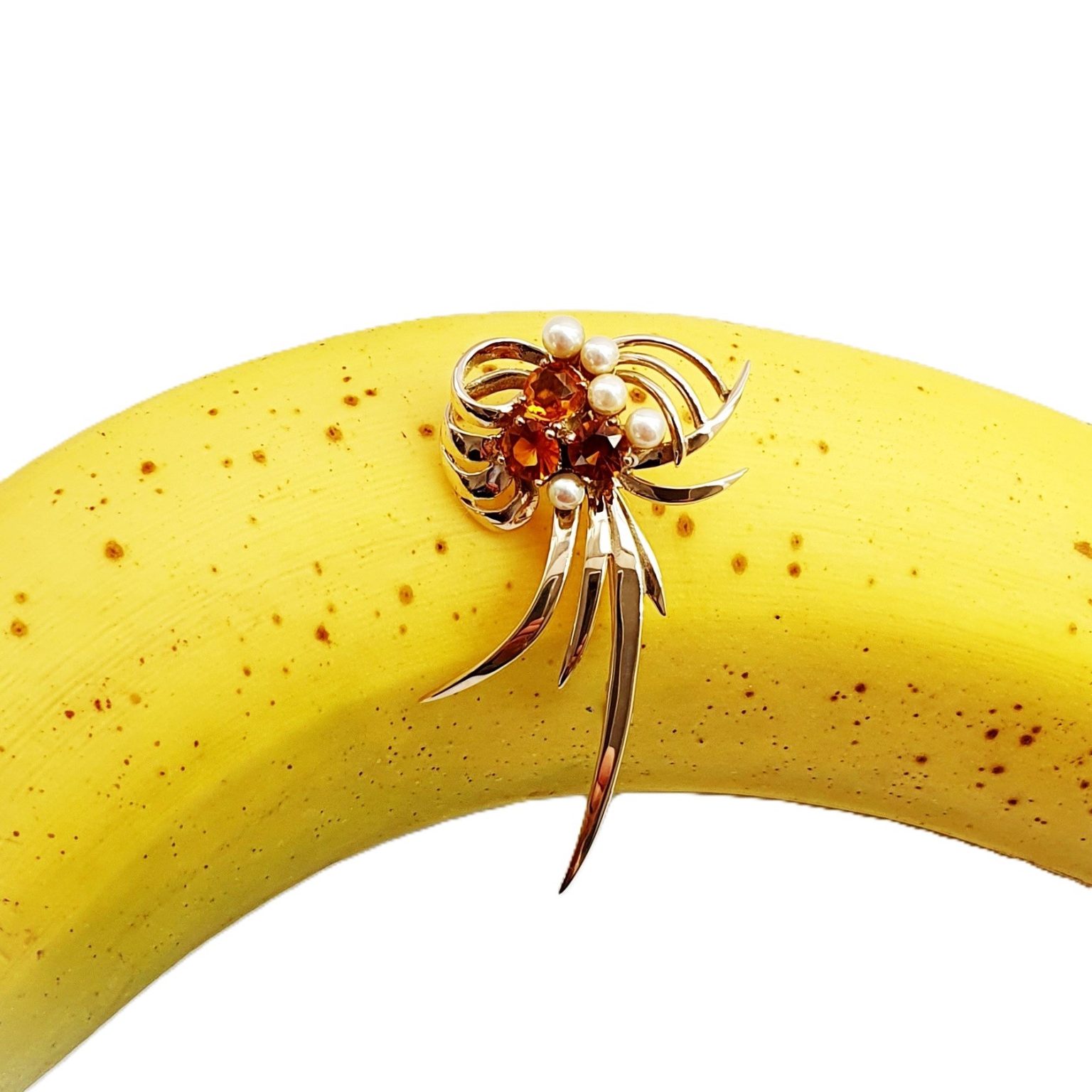 This gorgeous multi-loop bow brooch is crafted in 9ct yellow gold and features three golden yellow Citrines and five white pearls. Pictured on a banana.