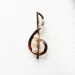 Polished 9ct yellow gold treble clef brooch with three 5.5mm cultured pearls to the centre. Close up.