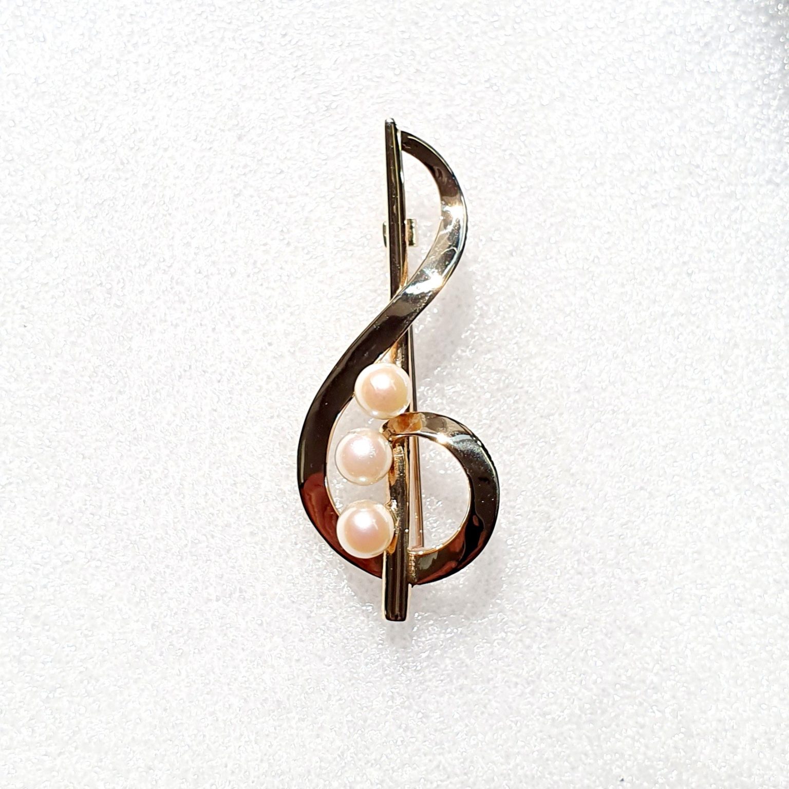 Polished 9ct yellow gold treble clef brooch with three 5.5mm cultured pearls to the centre. Close up.