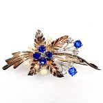 9ct Yellow Gold Ruby-Pearl Flower Brooch (36mm x 24mm) - Captivating floral elegance in 9ct yellow & white gold adorned with blue sapphires and cultured pearls. A masterpiece by The City of London Jewellers, showcasing nature's beauty and craftsmanship. One centre four-fern style leaf design with four sapphires and a diamond in the centre with a total of ten stems crossing behind set with two bright blue sapphires and a stem of a further four diamonds and four pearls. Front view close up.