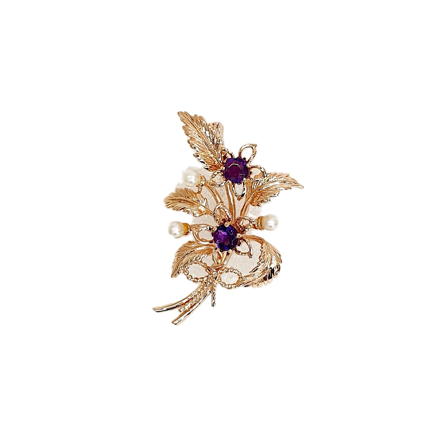 9ct rose gold flower brooch with five leaves, two round purple amethyst stones and three pearls made into a bouquet and tied to the bottom with a small twisted gold bow. Front view.