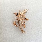 9ct rose gold flower brooch with five leaves, two round purple amethyst stones and three pearls made into a bouquet and tied to the bottom with a small twisted gold bow. Back view.