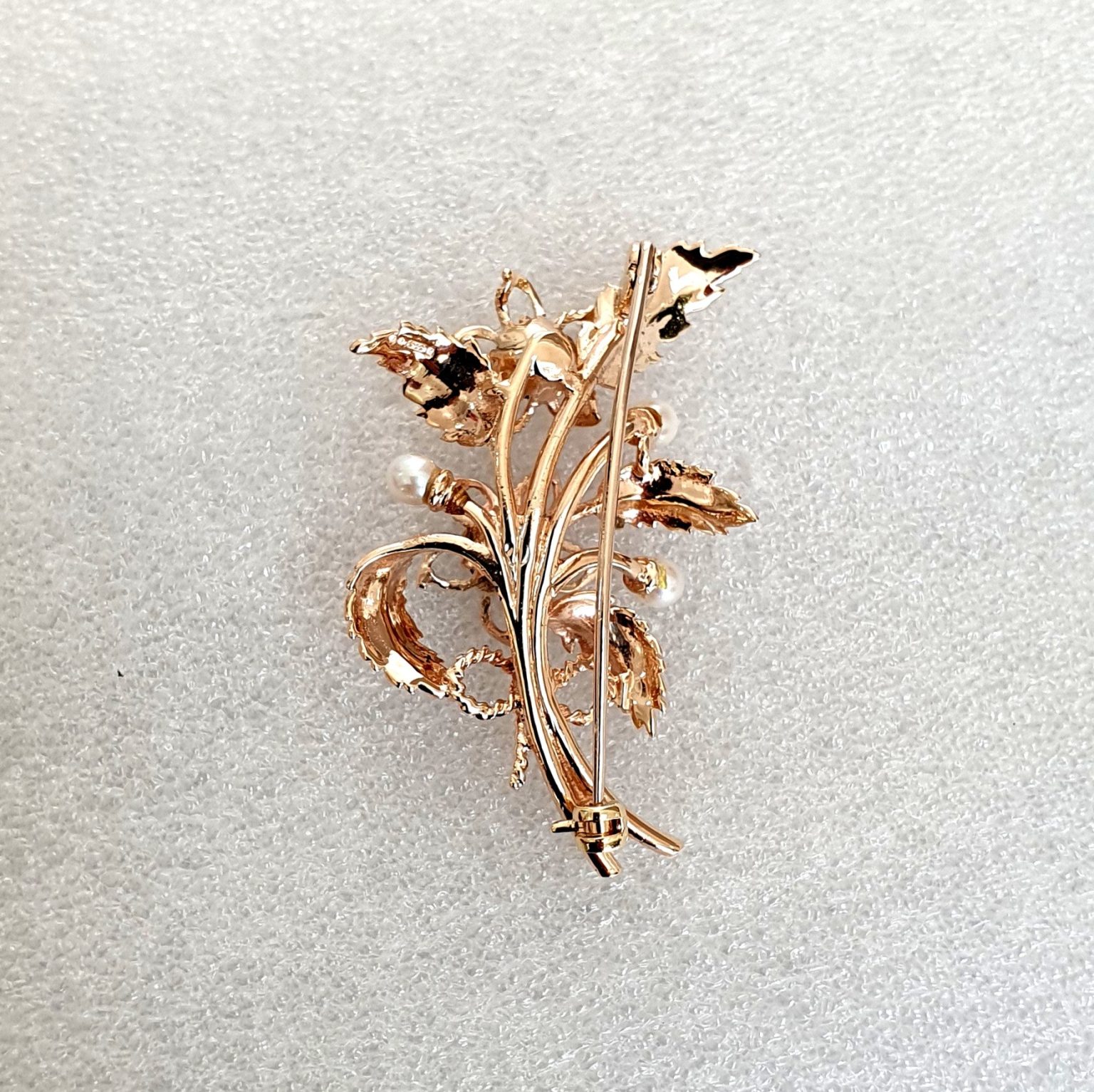 9ct rose gold flower brooch with five leaves, two round purple amethyst stones and three pearls made into a bouquet and tied to the bottom with a small twisted gold bow. Back view.