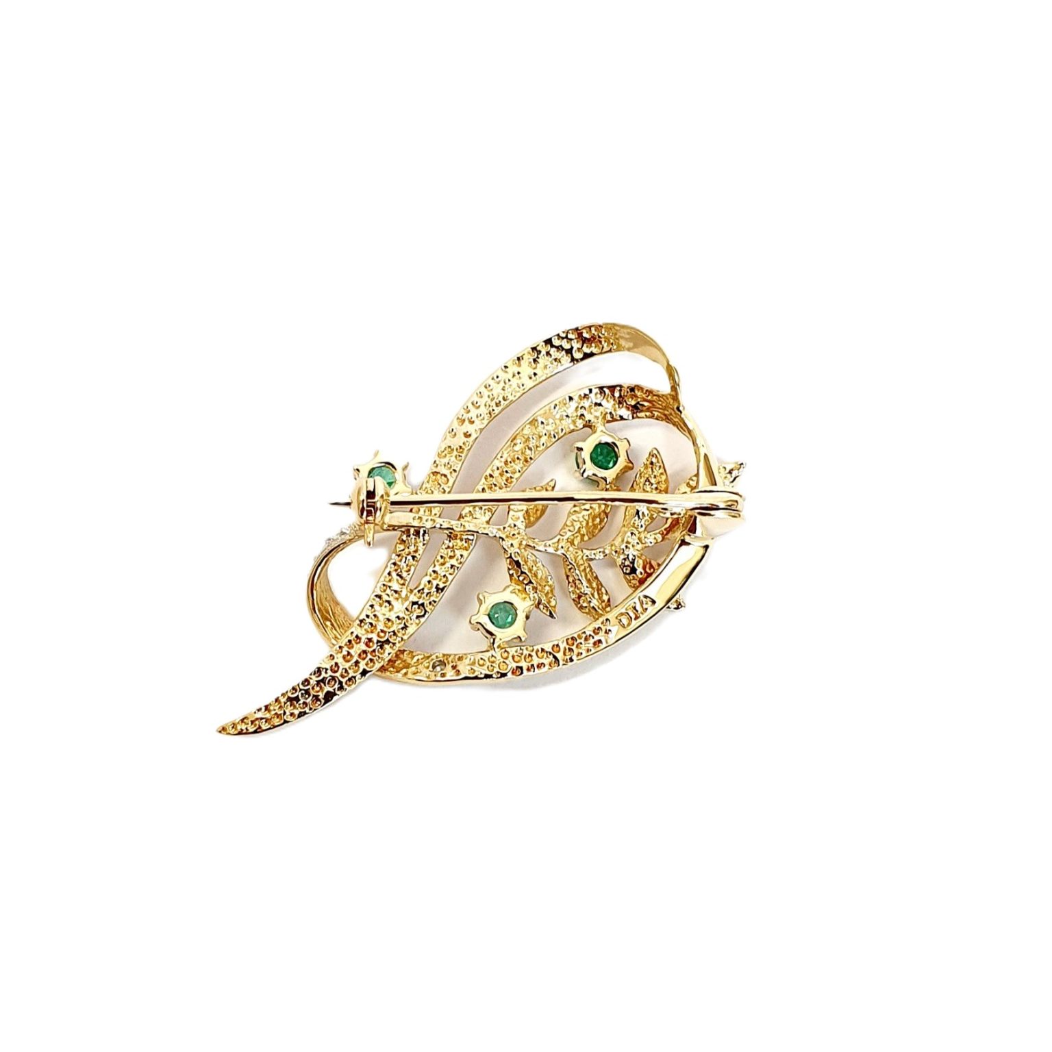 9ct yellow gold brooch with a sprig of seven leaves coming through a floral swirl of polished and barked yellow gold with three bright green emeralds & three sparkling diamonds set into a small white rhodium section, view of the back.