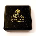 Black with gold speckles plastic box with cotton wool inside. Closed.