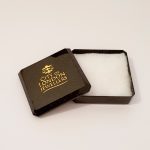 Black with gold speckles plastic box with cotton wool inside. Open.