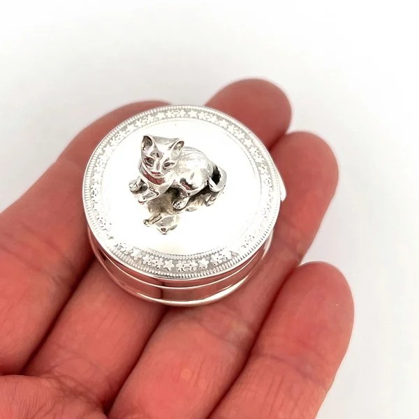 This Genuine silver cat pill box is a highly collectable gift for any cat lover. Made from the highest-quality sterling silver, the pill box is designed in London and made in England. Standing proud upon the lid, the sterling silver 3D cat is surrounded by detailed engraving around the edge of the lid.