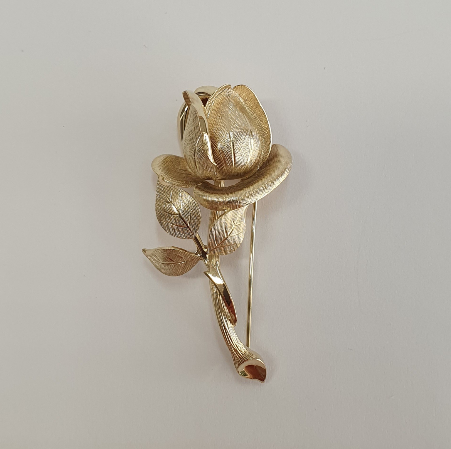 9ct yellow gold single rose broch with a textured pattern with polished highlights.