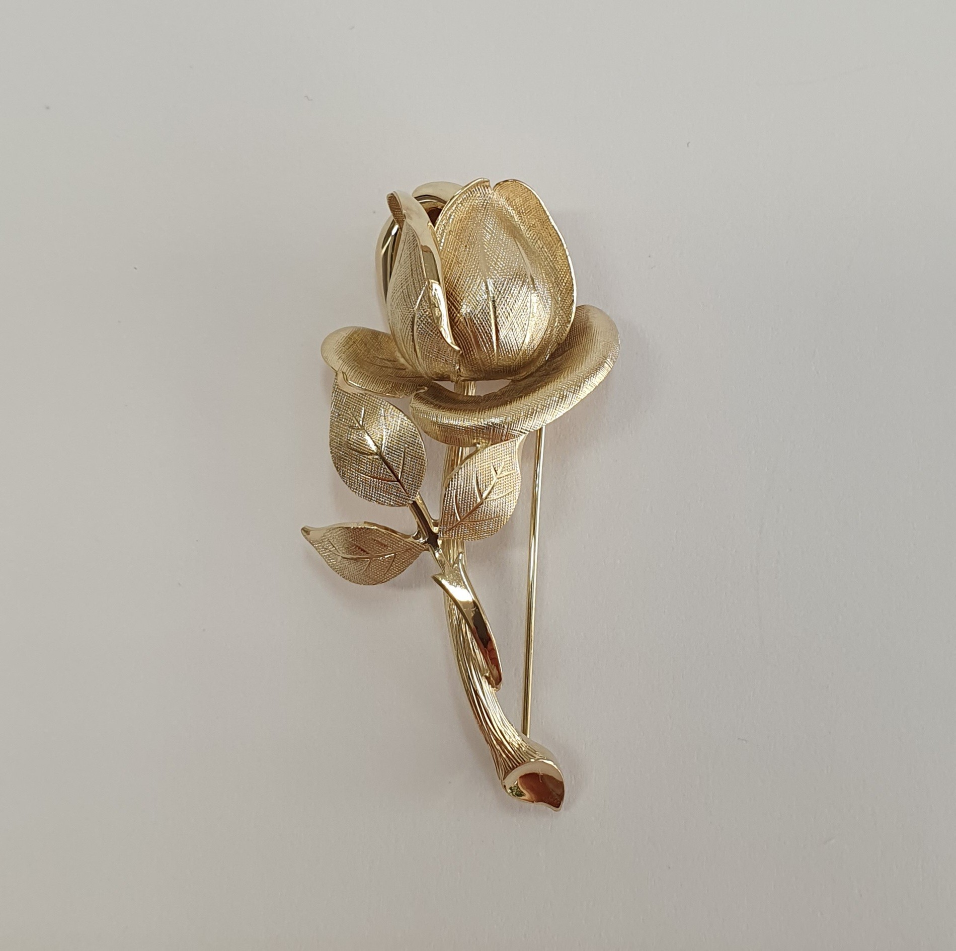 9ct yellow gold single rose broch with a textured pattern with polished highlights.