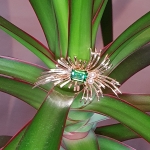 9ct yellow gold green tourmaline spray design brooch photographed on a plant.
