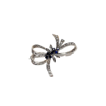 Front View "The Cropp & Farr 18ct white-gold brooch, featuring seven round sapphires and forty-one diamonds, elegantly arranged in a bow design. Stock number: BRQ00050."