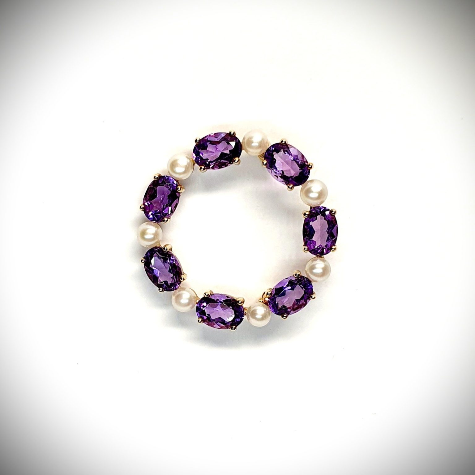 Seven round, beautiful cultured pearls with a further seven alternating stunning oval amethyst gemstones all set into a 9ct yellow gold circle wreath design brooch.