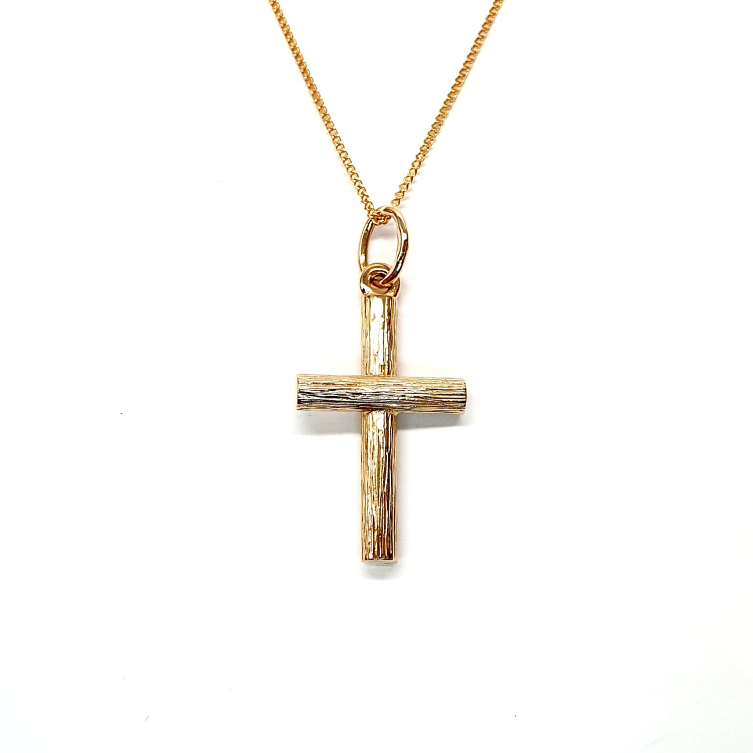 9ct gold cross pendant with hand-engraved tree bark texture.