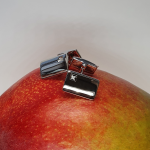 Elegant Hoxton Cuff Link fasteners with a curved rectangular design and a 1mm round diamond in a square box setting, resting on a mango.