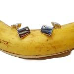 Elegant Hoxton Sleeve fasteners with a curved rectangular design and a 1mm round diamond in a square box setting, resting on a banana.