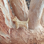 Terrier dog brooch pin pictured on a plant.