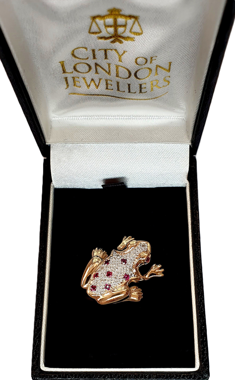 Broche grenouille en or jaune et blanc avec des rubis rouges et des diamants blancs.
