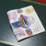 The plain polished back of the clip is shown with a 20-pound note pictured on a green book.