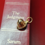 Handcrafted police helmet charm in gleaming 9-carat gold. picture on a red book