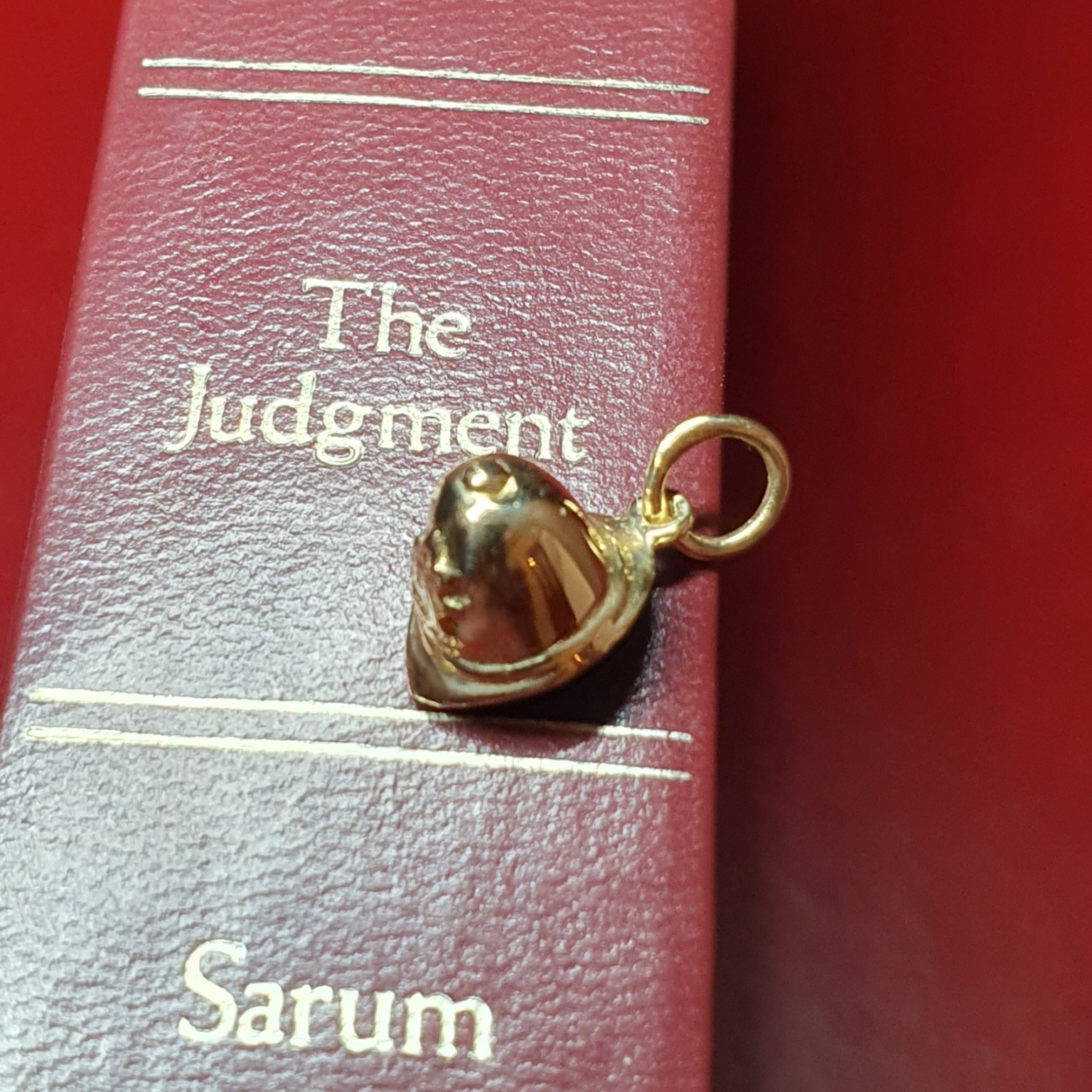 Handcrafted police helmet charm in gleaming 9-carat gold. picture on a red book