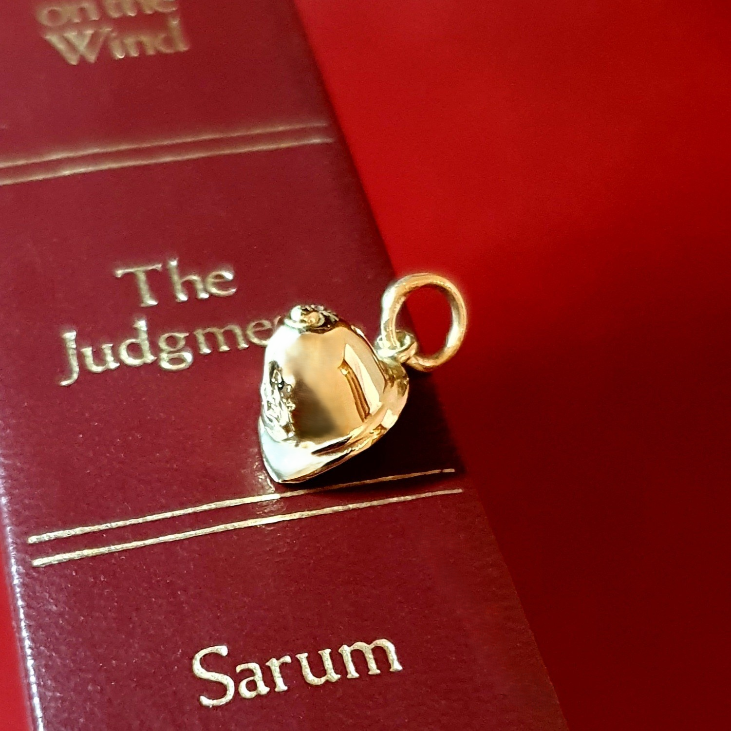 Handcrafted police helmet charm in gleaming 9-carat gold. picture on a red book