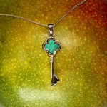 Front-facing on mango The necklace rests flat against the surface of a ripe mango, front-facing, with the vibrant gold contrasting the rich green malachite and the fruit’s yellow-orange hue.