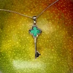 Front-facing on mango The necklace rests flat against the surface of a ripe mango, front-facing, with the vibrant gold contrasting the rich green malachite and the fruit’s yellow-orange hue.