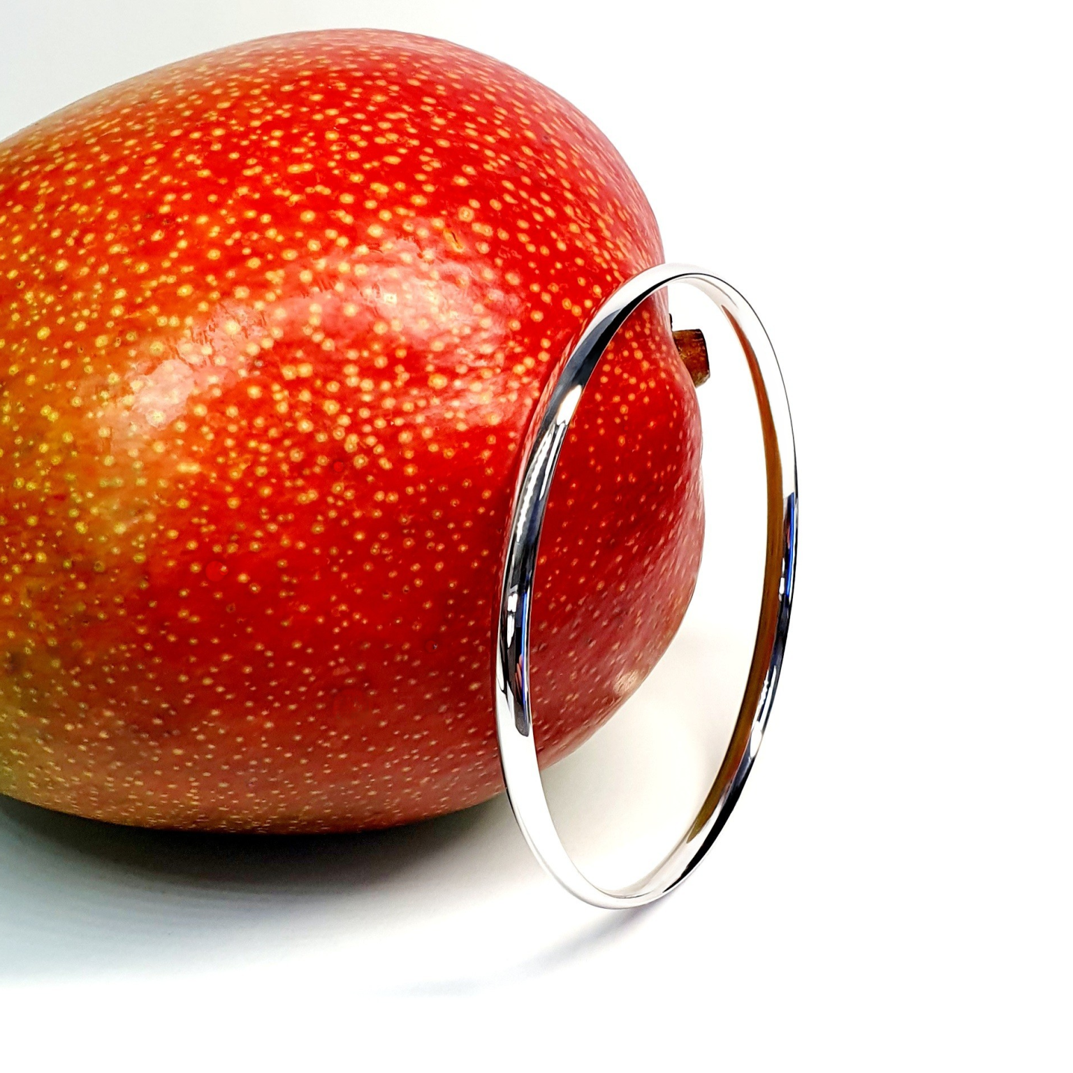 9ct white court shape bangle pictured with a mango.