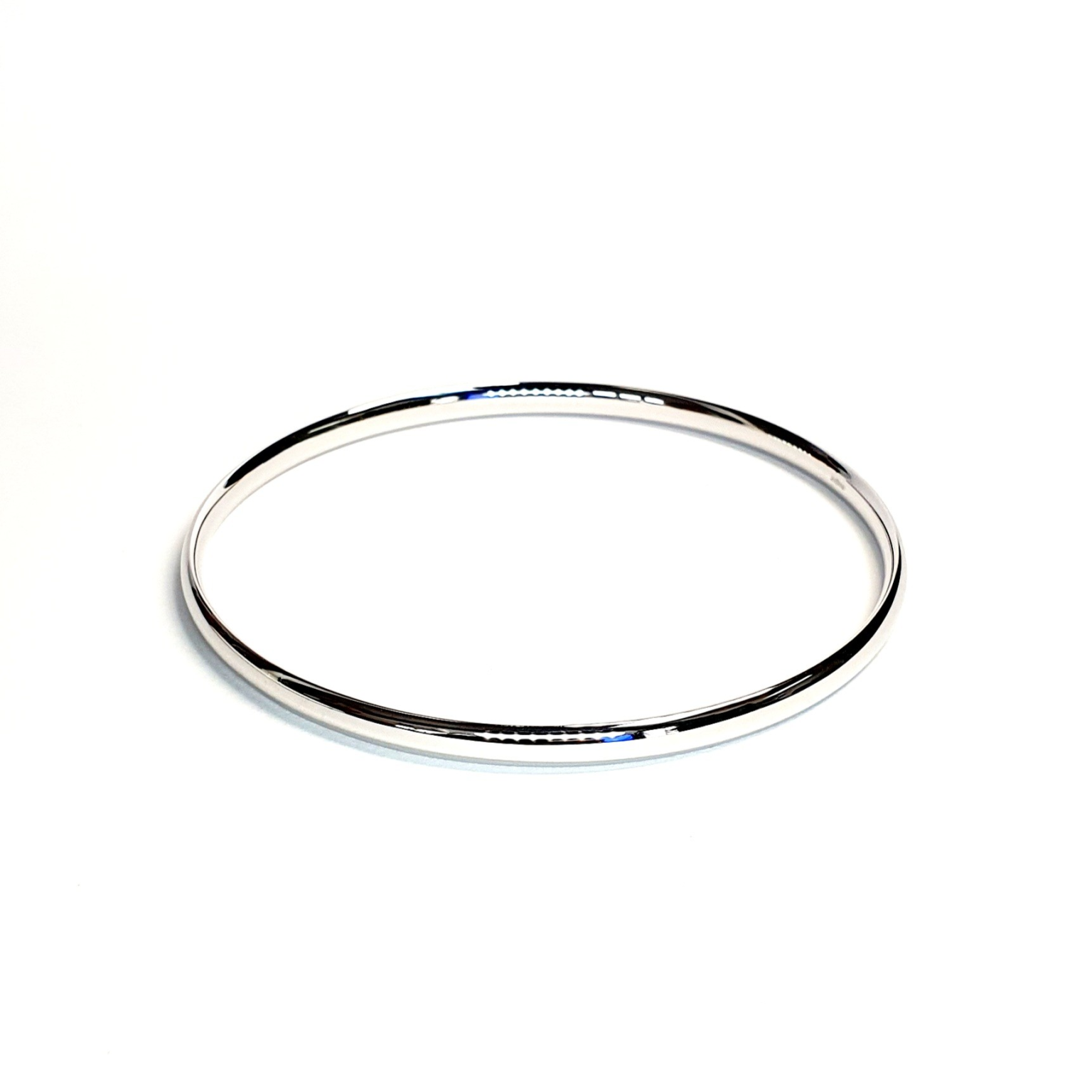 Comfort fit 4mm white gold stacking bangle laying on a flat surface.